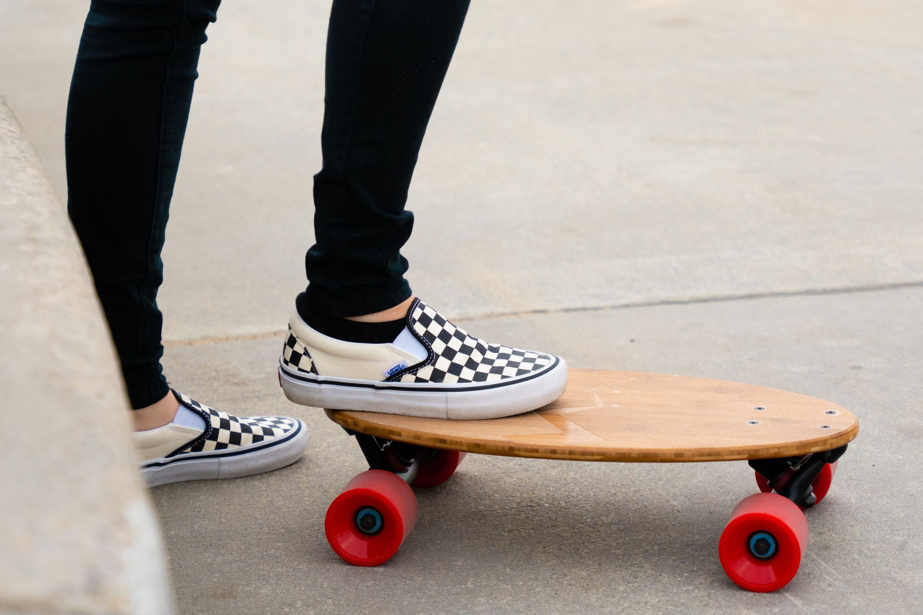 Close-up of checkered Vans on a mini longboard skateboard, ready to ride, showcasing its stylish, functional design.