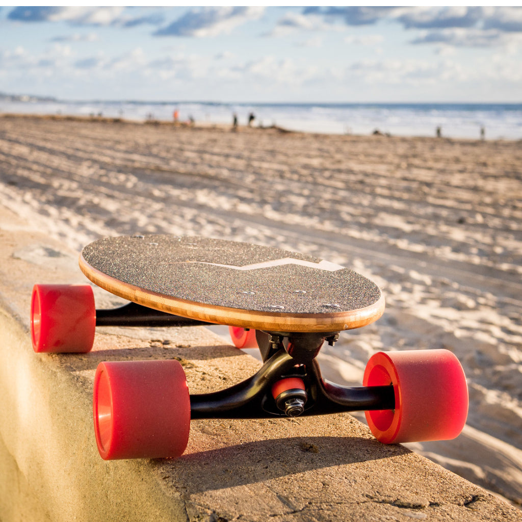 Eggboard's mini cruiser skateboard resting near the beach in San Diego, California, showcasing its stylish design and portability. The image highlights the perfect cruiser skateboard for beach adventures and casual rides.