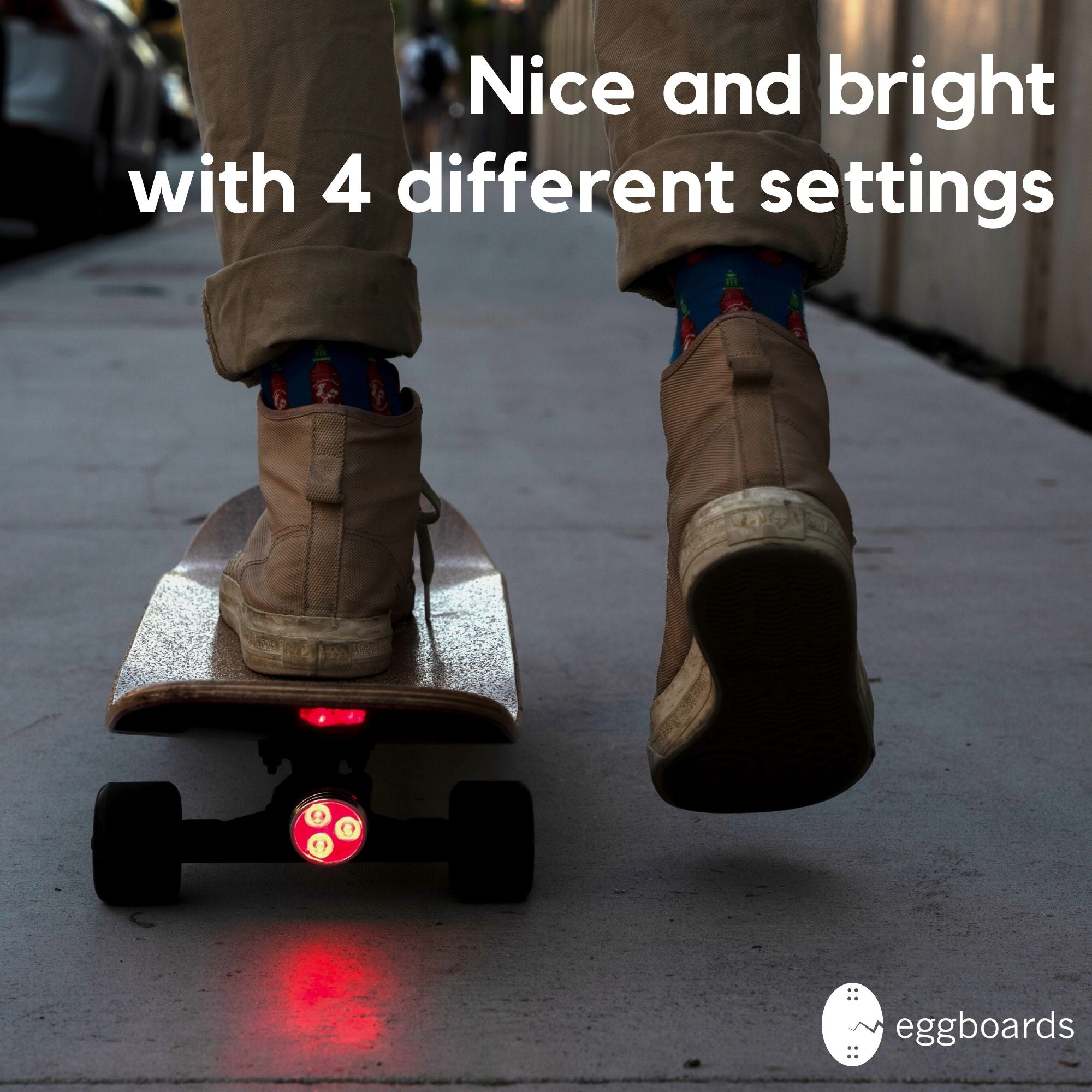 A guy riding his cruiser skateboard with an Eggboard LED tail light attached to the back truck under the kicktail for extra visibility and safety.