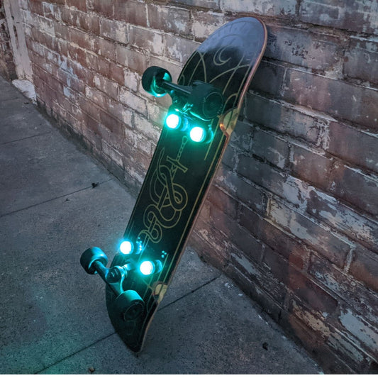 Closeup of a skateboard with four blue underglow lights leaning against a chair, showcasing the vibrant illumination that enhances visibility and style, promoting the launch of Eggboards' new underglow lights on December 1st.