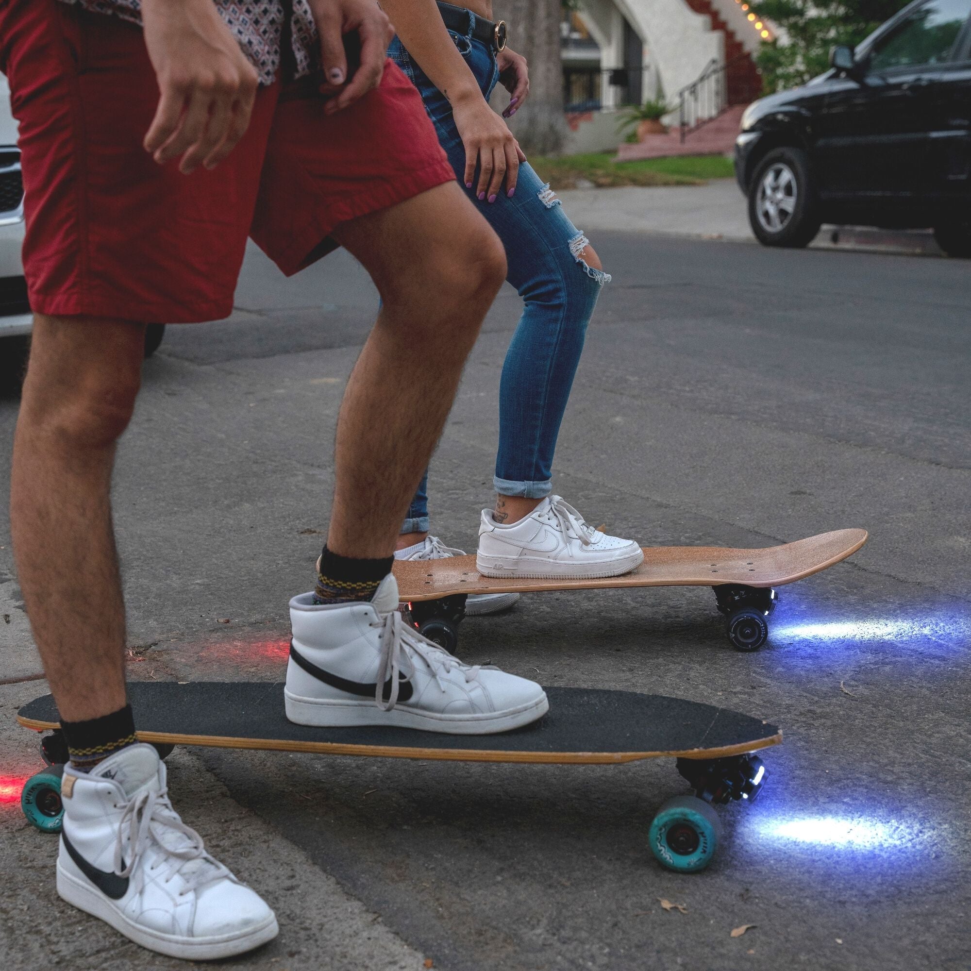 Two riders with skateboard lights on a mini cruiser and a longboard, ready to set off for a night cruise.