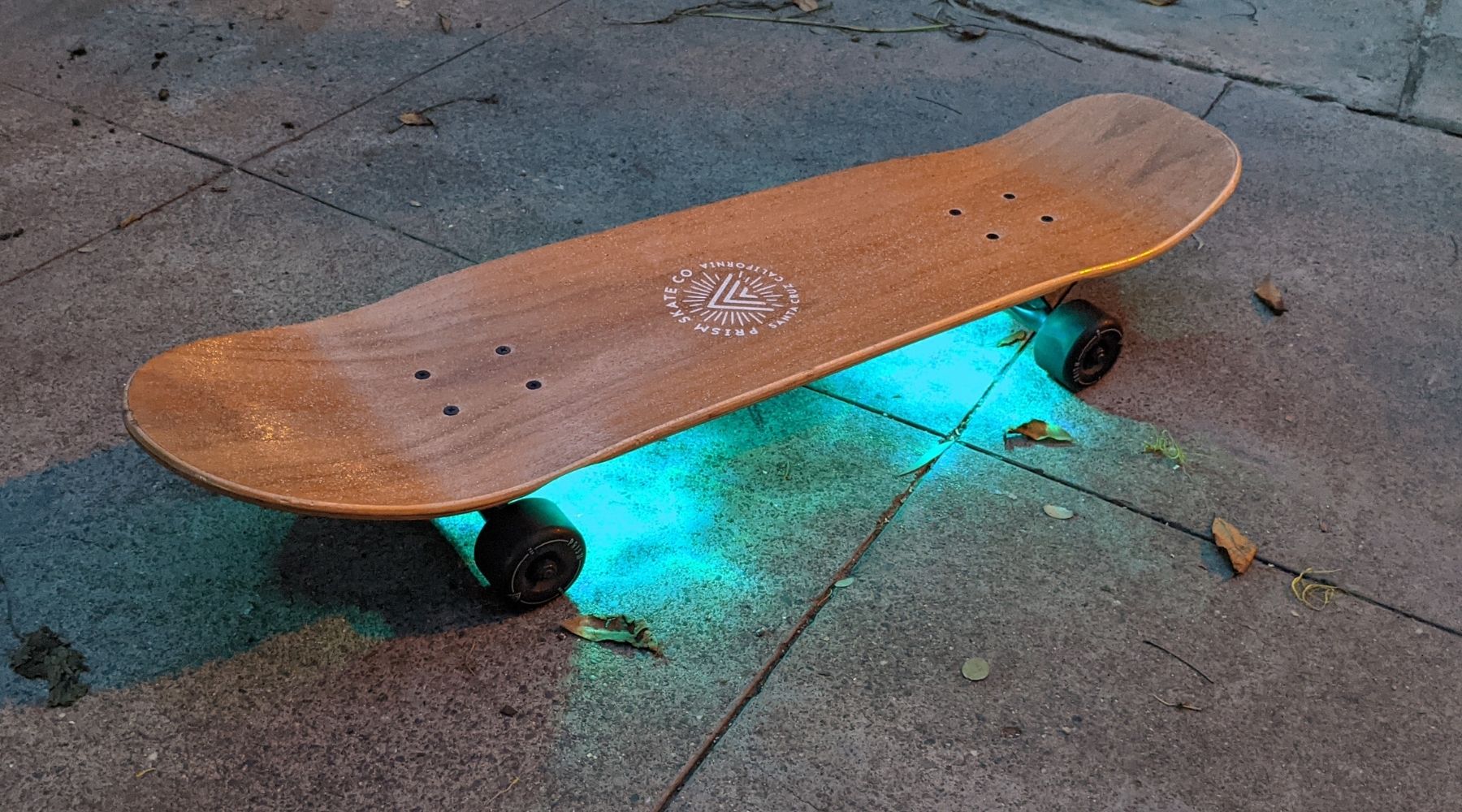 A cruiser skateboard illuminated with vibrant underglow lights, enhancing visibility at night, set against a blue aloha backdrop, showcasing the perfect blend of style and safety