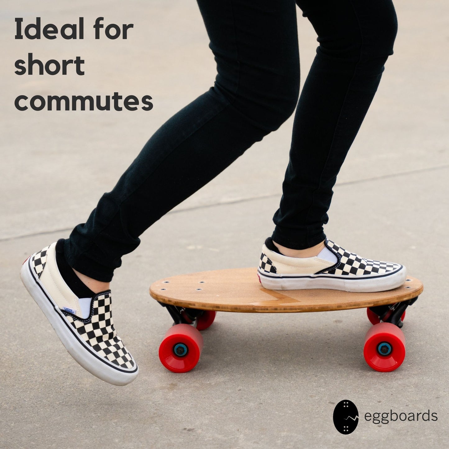 Closeup of a girl with checkered Vans shoes riding an Eggboard mini longboard cruiser featuring red wheels and a unique clear grip tape on the top of the skateboard deck. She is cruising on a paved road while wearing black jeans.