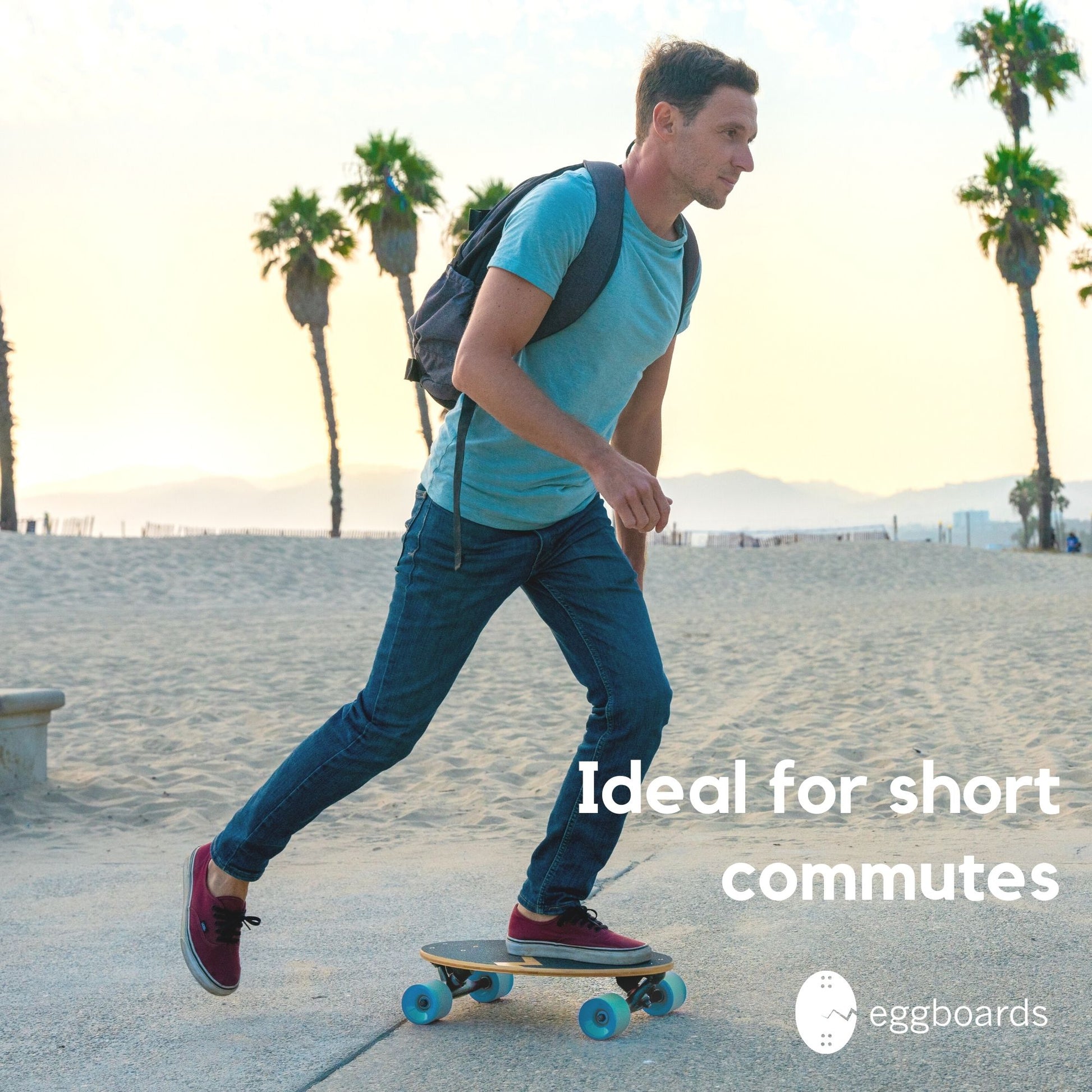 A guy skateboarding on an Eggboards mini longboard with blue wheels by the beach in Venice, California, with palm trees in the background. The overlay text reads "Ideal for short commutes," highlighting the board's portability for city rides.